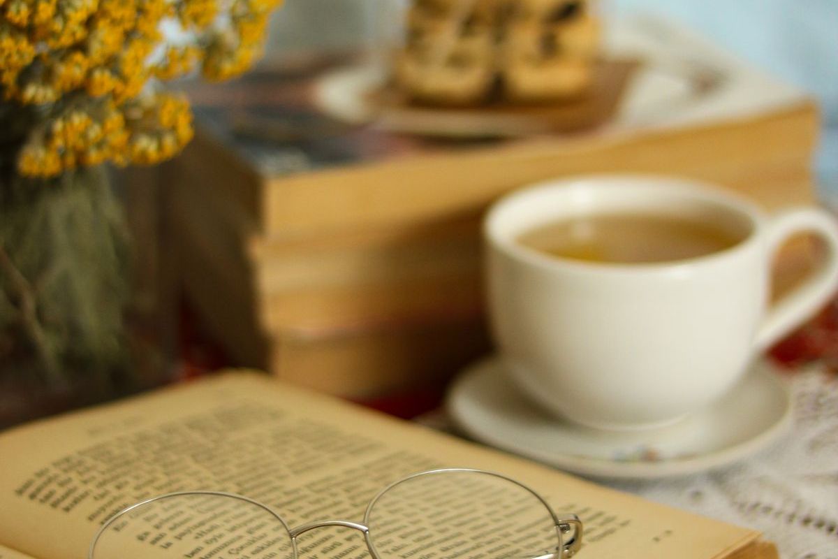 Reading glasses on an open book beside a cup of tea — practical gift ideas for seniors
