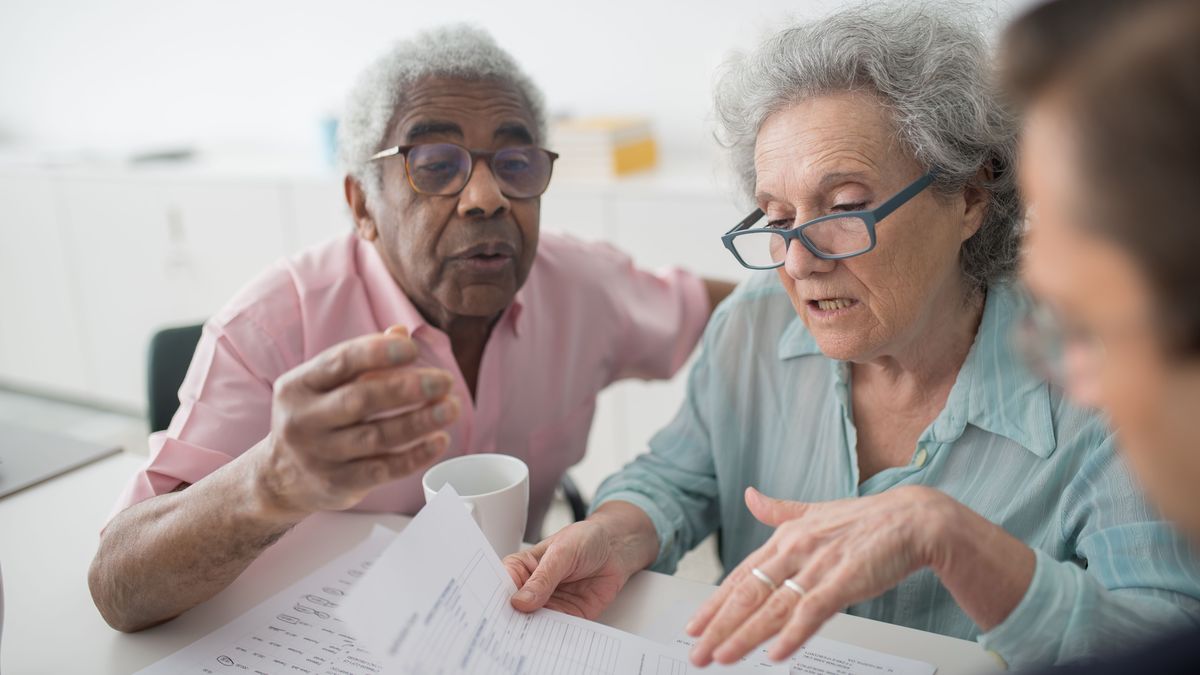 Two older adults working through paperwork together at a table